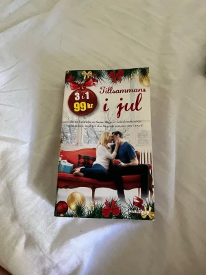 Tillsammans i jul antologi - Julig antologi med tre romantiska berättelser av Susan Wiggs, Barbara Dunlop och Lucy Clark. Omslaget är dekorerat med julkulor, granris och ett par som myser på en röd soffa. Perfekt för dig som älskar romantik och julstämning.