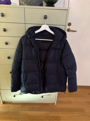 North Wood vinterjacka/täckjacka - Exemplar 2: Denna vinterjacka har jag använt någon enstaka gång i fjällen när jag åkt slalom, har två exemplar av denna jacka och säljer nu båda.   - Äldre säsongsmodell.  - Är asymmetriskt skuren, vilket innebär att den är något längre i modellen baktill. Storlek: M - Ordentlig fast huva, en rejäl innerficka, fickor på båda sidor med knappstängning - Justerbar dragsko nedtill i fållen för att kunna stänga ute vind - Material: Shell: 100% NYLON, padding: 100% POLYESTER, Lining: 100% POLYESTER