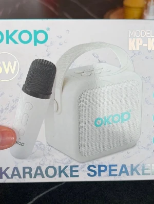 OKOP karaoke högtalare med mikrofon -  bärbar karaokehögtalare från OKOP med matchande mikrofon. Högtalaren har en fyrkantig form, tygfront och praktiskt handtag upptill. Perfekt för att ta med sig och sjunga var som helst. Snygg och modern design med tydliga knappar på ovansidan.