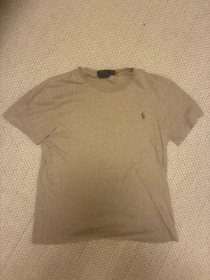 Beige basic t-shirt i bomull - Enkel och stilren beige t-shirt med korta ärmar och rund halsringning. Tillverkad i mjuk bomull som känns skön mot huden. Perfekt att matcha med jeans eller shorts för en avslappnad look.