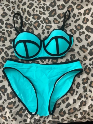 Turkos bikini med svarta detaljer - Snygg turkos bikini med svarta kontrastkanter och bygel-bh. Bikinin har justerbara axelband och en modern, sportig look. Perfekt för stranden eller poolen!