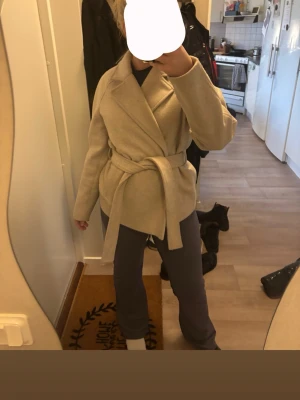 Beige kappa med knytskärp - Hej! Säljer denna vår jacka då den inte kommer till användning. Den är använd men väldigt bra skick!