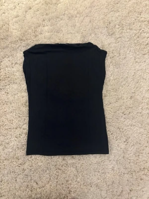 Två ärmlösa toppar i svart och rosa - Säljer två basic toppar, en i navy och en i ljusrosa. Båda är ärmlösa med enkel, rak passform som sitter tajt och rund halsringning. Perfekta att matcha till jeans eller kjol. Materialet känns mjukt och stretchigt, troligen bomull eller bomullsblandning.