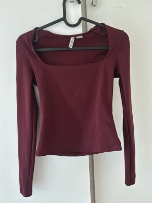 Vinröd långärmad topp H&M - Snygg vinröd långärmad topp från H&M  med fyrkantig urringning. Tillverkad i mjukt och stretchigt material som sitter skönt på kroppen. Perfekt att matcha med både jeans och kjol för en trendig look.