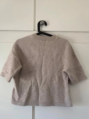 Beige stickad tröja & Other Stories - Säljer denna jättefina beiga  kortärmade stickad tröja från & Other Stories. Knappast använd och i jättefint skick. Pris kan diskuteras!