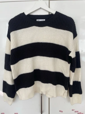 Randig stickad tröja från sinsay - Säljer en svartvit stickad tröja från sinsay med breda horisontella ränder. Tröjan har rund halsringning, lång ärm och är gjord i ett tjockare, ribbstickat material. Perfekt för dig som gillar en avslappnad och trendig look.