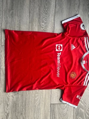 Manchester United Hemmatröja 21/22 – Cristiano Ronaldo #7 – Storlek S - Klassisk Manchester United-hemmatröja från säsongen 2021/22, året då Cristiano Ronaldo återvände till Old Trafford! • Lag: Manchester United • Spelare: Cristiano Ronaldo #7 • Storlek: S (Small) • Säsong: 2021/2022 • Märke: Adidas • Skick: Fint skick. Tryck och loggor är välbevarade. • Detaljer: Inkluderar Premier League-märke på ärmen och det ikoniska namntrycket på ryggen. En modern klassiker och ett måste för alla United-fans eller Ronaldo-samlare. Jag packar noga och skickar snabbt! 📦🔴 