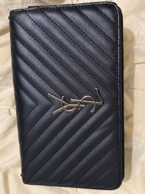 Svart quiltad handväska med silverdetaljer - Snygg svart handväska i quiltad design med diagonala sömmar och silverfärgade metalldetaljer. Väskan har en stilren, rektangulär form och är tillverkad i konstläder. Perfekt accessoar för dig som gillar en klassisk men trendig look. (Utan kjedja )