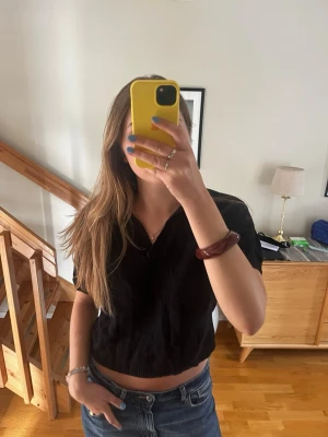 Svart stickad topp med v-ringning - Säljer en svart stickad  topp med v-ringning och korta ärmar. Perfekt för dig som gillar en enkel och stilren look. 