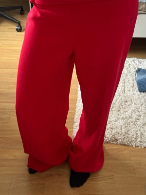 Röda mjukisbyxor från Zara Woman - Snygga röda mjukisbyxor från Zara Woman med breda ben och hög midja. Perfekt för dig som gillar att chilla i stil. Materialet är mjukt och skönt, och färgen är riktigt poppande röd. Passar dig som vill ha en avslappnad look. Skriv om ni har frågor eller vill ha fler bilder!