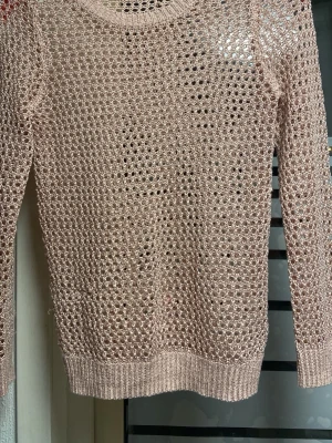 Ljusrosa nätstickad tröja H&M - Säljer en ljusrosa nätstickad tröja från H&M. Tröjan har lång ärm, rund halsringning och ribbade muddar vid ärmslut och nederkant. Materialet är tunt och luftigt, perfekt för lager på lager och en avslappnad stil.