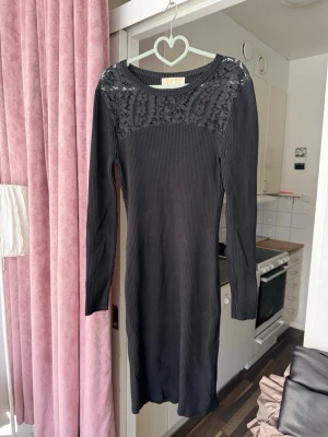Michael Kors klänning – storlek L  ny - Svart ribbad klänning från Michael Kors med spetsdetaljer upptill. Figurnära modell i stretchigt material, bekväm och elegant. Passar både vardag och kväll.  Storlek: L Skick: mycket bra Pris: 350 kr  