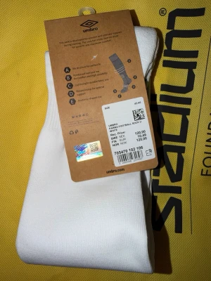 Vita fotbollsstrumpor från Umbro - Säljer ett par vita Parma Football Sock från Umbro i storlek 43-45. Strumporna är tillverkade i ett slitstarkt och lätt material med förstärkt häl och tå för extra hållbarhet. Perfekta för fotbollsträning eller match.