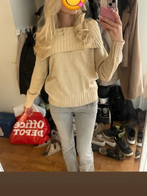 Beige stickad tröja med bred krage - Säljer en beige stickad tröja med bred ribbad krage som går över axlarna. Tröjan har lång ärm och ribbade muddar vid ärmslut och nederkant. Perfekt för dig som gillar en enkel men snygg look till vardags. Tröjn har inga lappar. Jag är 170cm lång och har S/XS i storlek vanligtvis. Aldrig använd. 