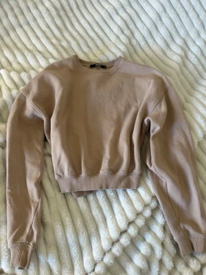 Beige sweatshirt från Bik Bok - Säljer en beige sweatshirt från Bik Bok. Utan luva och tryck. Tröjan har rund halsringning, långa ärmar och ribbade muddar vid ärmslut och nederkant. Tillverkad i mjukt sweatshirtmaterial som är perfekt för en avslappnad och trendig look. 