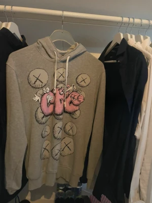 Grå hoodie | Comme des garçons X Kaws  - En riktigt snygg och trendig grå hoodie från Comme des garçons play som har en collab med Kaws. Hoodien är använd ett fåtal gånger då den är för liten. Hoodien var limited edition och går ej att köpa längre, därav ett lite högre pris! Storleken är L men skulle säga att den passar M! Skriv privat för fler bilder eller vid funderingar!!