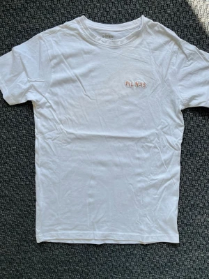 Handbroderad vit t-shirt från Denim Project - Vit T-shirt med handbroderad text ”Fil 4:13”. ”Allt förmår jag i honom som ger mig kraft”