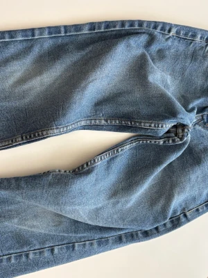 Blå klassiska jeans 140 cm Levis - Ett par klassiska blå jeans i rak modell med normal passform. Jeansen har en tidlös tvätt och är tillverkade i bomull. Perfekta för en avslappnad och stilren look.