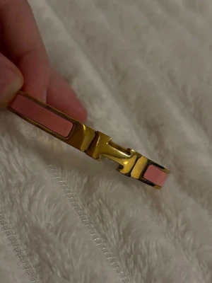 Rosa och guld armband - Säljer ett ikoniskt Clic H armband i guldfärgad metall med ljusrosa emaljdetaljer. Armbandet har en stilren och elegant design med det klassiska H-spännet framtill. Helt ny! Minsta storleken.🧡