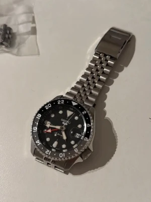 Seiko 5 Sport GMT - Seiko herrklocka, Fullständigt namn - Seiko 5 sport GMT SSK00k1k1, Nytt pris som jag betalade - 5998kr, Nästan helt oanvänd, köptes 2024-11-15 på Kent Watch&jewellery i Sundsvall, kvitto och Försäkringsbevis finns och skickas med.