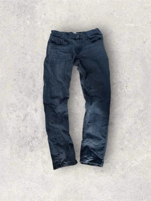 Levi’s 512 Slim Taper Jeans – Grå/Svarta - Säljer ett par Levi’s 512 Slim Taper jeans i grå/svart tvätt. Slim fit upptill och smalare ner i benen.  Storlek: Passar ungefär 12-åring (12A) beroende på längd.  Skick: Bra skick överlag. Läderlappen bak där Levi’s-märket sitter är sliten och en del saknas (syns på bild). Annars fungerar jeansen bra.  Detaljer: 	•	Modell: Levi’s 512 Slim Taper 	•	Färg: Grå / washed black 	•	Herr / ungdom 	•	Klassisk denim  Skriv om du vill ha fler bilder eller mått! 📩