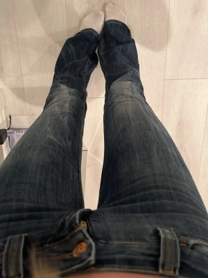 Mörkblå bootcut jeans från cheap Monday/weekday - Säljer ett par mörkblå bootcut jeans från weekday med snygga slitningar och klassiska gula sömmar. Jeansen har dragkedjegylf och kopparfärgad knapp med cheap Monday -logga. Perfekta för en avslappnad och trendig look. Jeansen är endast använda 2 gånger och jag är 1,70 och har relativt långa ben men dessa går ända ner till fötterna.