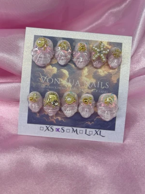 Starla (S);Short Oval - Handgjorda press-on naglar i ljusrosa med marmorerad effekt och guldstjärnor, pärlor och glitter. Naglarna har en rund form och är dekorerade med unika detaljer som gör dem riktigt iögonfallande. Perfekt för dig som vill ha något extra.S: 15 mm, 11,5 mm, 12 mm, 11 mm, 9 mm 