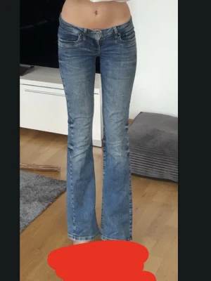 Blå bootcut jeans från LTB - LTB jeans med bootcut passform och låg midja. Klassisk femficksmodell med slitningar och snygg tvätt. Perfekta för dig som gillar en avslappnad men ändå trendig look. Storlek 25/32 