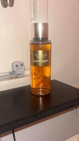 Victoria's Secret Coconut Passion mist - Fräsch doftmist från Victoria's Secret i doften Coconut Passion. Flaskan är genomskinlig med guldigt lock och etikett, och innehållet har en varm, gyllene färg. Doften har inslag av kokos och vanilj, perfekt för dig som gillar tropiska vibbar. Använd, ungefär 95% kvar.