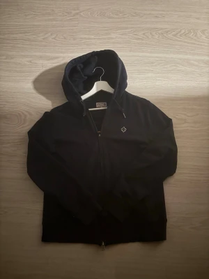 Morris - Svart hoodie med dragkedja från Björn Borg. Klassisk modell med huva och dragsko, samt broderad logga på bröstet. Tillverkad i mjukt bomullsmaterial som är skönt att ha på sig. Perfekt för en avslappnad och stilren look.