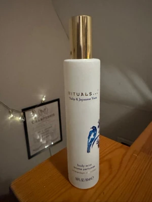 Rituals Tulip & Japanese Yuzu Body Mist - Fräsch body mist från Rituals med doft av tulpan och japansk yuzu. Flaskan är vit med blått fågelmotiv och har en elegant guldfärgad kork. Perfekt för dig som vill ha en lätt och blommig doft i vardagen.