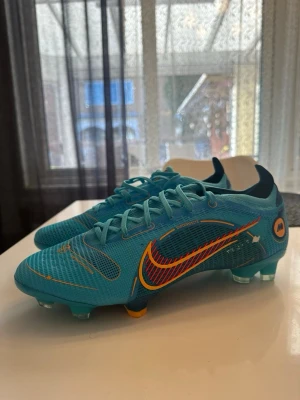 Nike Mercurial 14 blå fotbollsskor - Pris går att diskutera ……Säljer ett par Nike Mercurial fotbollsskor i en fräsch blå färg med orange och gula detaljer. Skorna har låg profil, snörning och mönstrad ovandel i syntetmaterial för bra bollkontroll. Sulan har fasta dobbar för spel på gräs. Perfekta för dig som vill sticka ut på planen….. använda max 1-3 gånger. Riktigt fräscha och tog bort initialer på sidan, syns knappast.