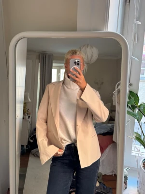 Beige kavaj med klassisk passform - Snygg beige kavaj med klassisk krage och enkelknäppning. Kavajen har raka axlar (axelvaddar) och är tillverkad i ett slätt material som ger ett stilrent intryck. Perfekt att matcha med jeans eller kostymbyxor för en trendig look.⭐️❤️