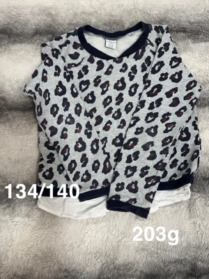 Grå leopardmönstrad tröja  - Säljer en grå långärmad tröja från Polarn o pyret med leopardmönster. Tröjan har ribbade muddar vid hals, ärmslut och nederkant. Perfekt för dig som gillar djurmönstrat och vill ha en trendig look.🌸 Fint använt skick. Storlek 134/140 