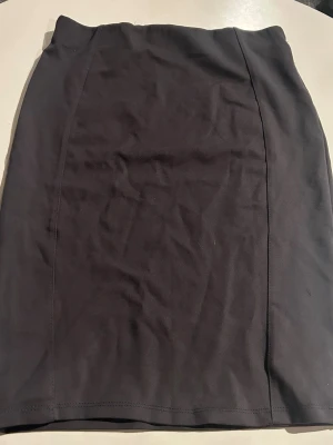 Knälång kjol  - Mörkgrå kjol ej säker på storlek men passar mig som använder S i underdelar. Den är utformad med en rak passform och har en slät yta. Den är i tjockare material och har prislappen kvar och den är stretchig