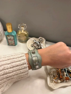 Balenciaga armband  - Säljer detta sååå snygga balenciaga armband i en mintgrön färg🪽 Köpt på plick för 1500kr‼️På sista bilden finns det kvitto från säljaren då hon köpte armbandet på Vestiaire.   Armbandet är väl använt därav pris. Skicket ser man tydligt på bilderna😇 Skriv till mig för fler frågor🪽