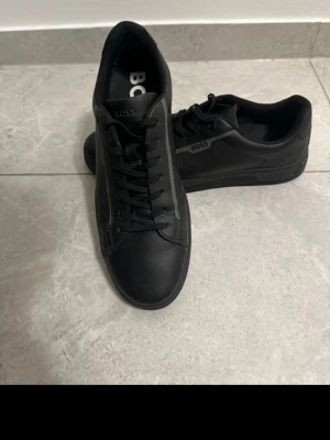 Svarta sneakers från BOSS - Säljer mina Hugo boss skor säljer det eftersom fick dem små i present av kompisen har haft dem länge i garderoben utan att det gör någon nytta, dem är knappt använda. Priset kan diskuteras vid snabb affär 