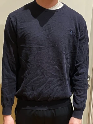 Mörkblå tröja från Polo Ralph Lauren - Mörkblå långärmad tröja från Polo Ralph Lauren med diskret broderad logga på bröstet. Tröjan har rund halsringning och ribbade muddar vid ärmslut och midja. Perfekt för en clean och enkel stil. Stolek XL men passar även L!