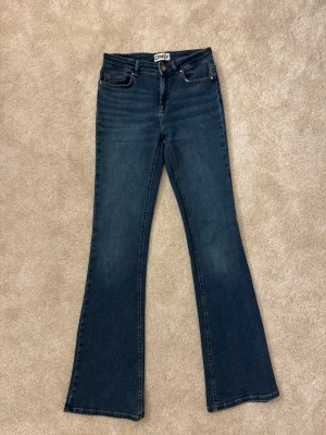 Mörkblå bootcut jeans från ONLY - Mid waist och M i midjestorlek och 34 i benlängd.(Finns en fläck som inte går bort på en sidan - se bild 4)