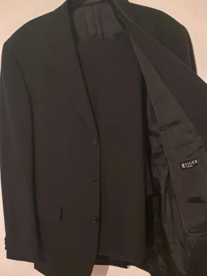 Full kostym  - Stl M på byxor - L på kavajen plagen är använda en gång!   Elegant kostym från Tiger of Sweden i exklusivt italienskt tyg från Reda.  Stilren och tidlös kostym tillverkad i högkvalitativ ull från den välrenommerade italienska väveriet Reda. Kostymen har en klassisk passform med kavaj och matchande byxor, perfekt för både formella tillfällen, arbete eller fest.  Ett premiumplagg som kombinerar skandinavisk design med italiensk textiltradition för komfort, kvalitet och ett sofistikerat uttryck. 👔✨