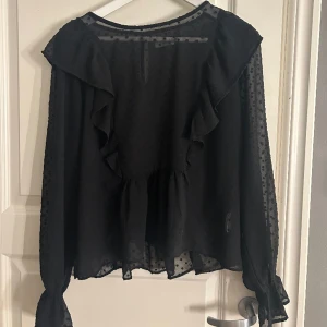 Blus - Svart blus med volanger. Den är i strl L men jag tycker den känns mycket mindre i storleken