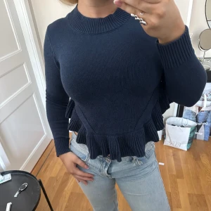 Marinblå stickad tröja - Sååå söt marinblå tröja med puplum liknande detaljer. Säljer då den är lite för liten och inte kommer till användning längre. Sparsamt använd!!