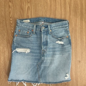 Levis jeanskjol  - Kort Levis jeanskjol i blå färg. I storlek W27, skulle säga att den motsvarar XS. Använd ett par fåtal gånger. 