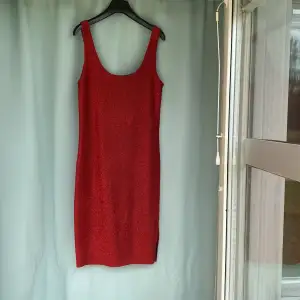 Röd ärmlös klänning  i glitter tyg använd enstaka gång  58% Polyamid 22% Polyester  12% Metalic Fibres 8%Elastic 