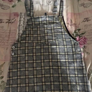 Rutig hängselkjol  - Rutig hängselkjol med ficka fram till 