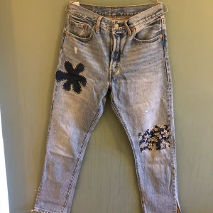 Levis 501 unika  - Ett par unika Levis 501, slits vid bensluten, lagade på två ställen (se bilder, blomma och lapp på knät). W:28 L:30