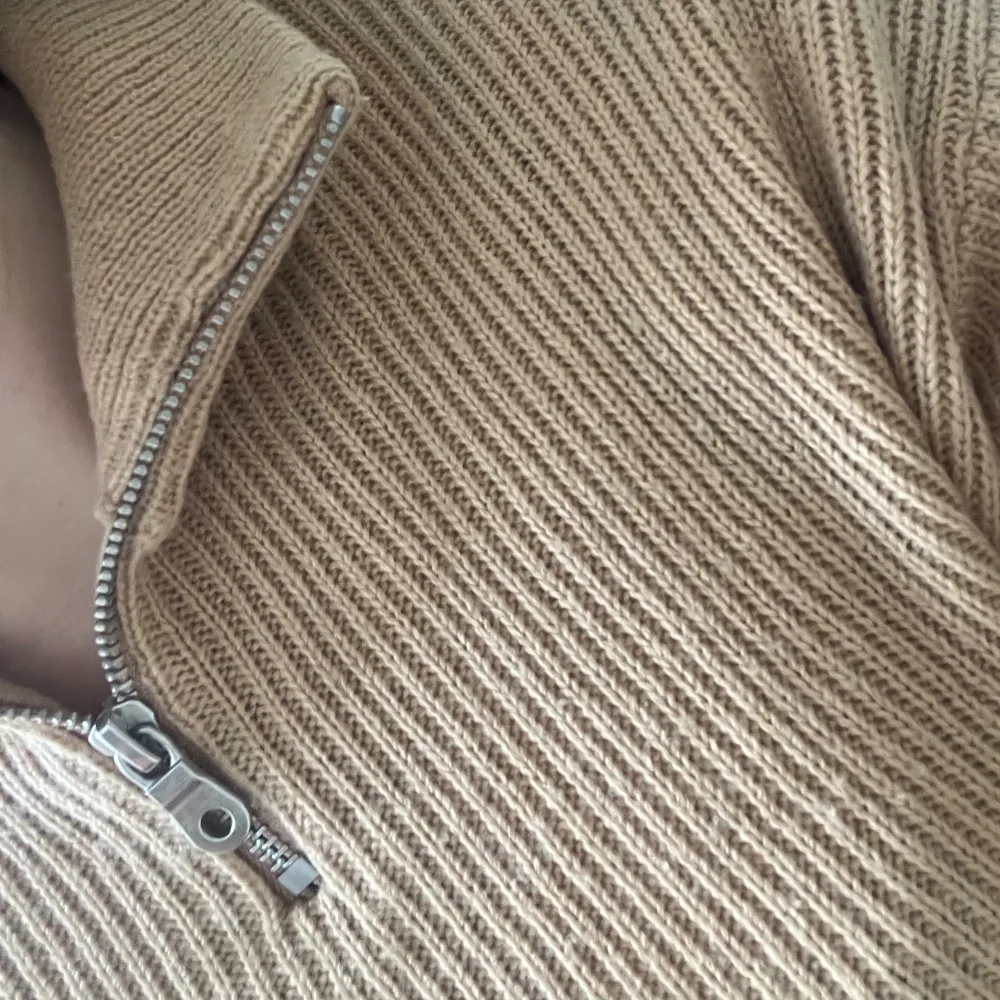 En enkel men fin stickad tröja. Har en dragkedja som gör den extra unik. Den är bege/brun. . Tröjor & Koftor.