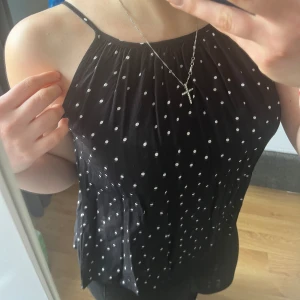 Topp - Gullig topp till sommaren.  Svart med vita prickar. Luftig och skön. Väldigt tun men inte genomskinlig. 
