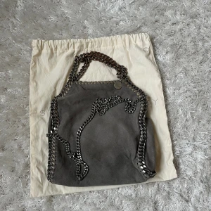 Stella McCartney väska  - Säljer denna Stella McCartney väska, modell mini tote. Den är äkta och man får med påsen. Den är väl använd och har därmed en del slitningar, hör av dig om du vill ha fler bilder. Har du någon fråga är det bara att höra av dig🫶🏻