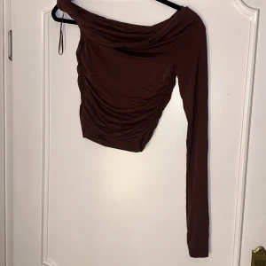 One shoulder tröja - Tröjan är i gott skick, använd fåtal gånger. Tröjan är one shoulder och sydd på sidorna för detaljer. 